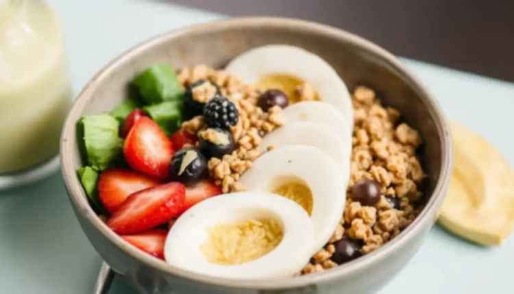 Hard-boiled egg slices with granola, fruit, and spinach in a bowl